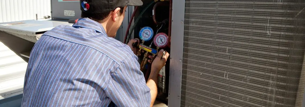 HVAC technician servicing a condenser unit in Larkin